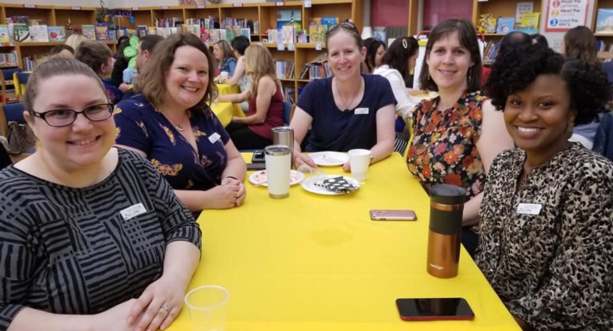 Women smiling and sitting at a table in the media center 